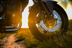 Motorcycle wheel visible in front of a sunset in the grass